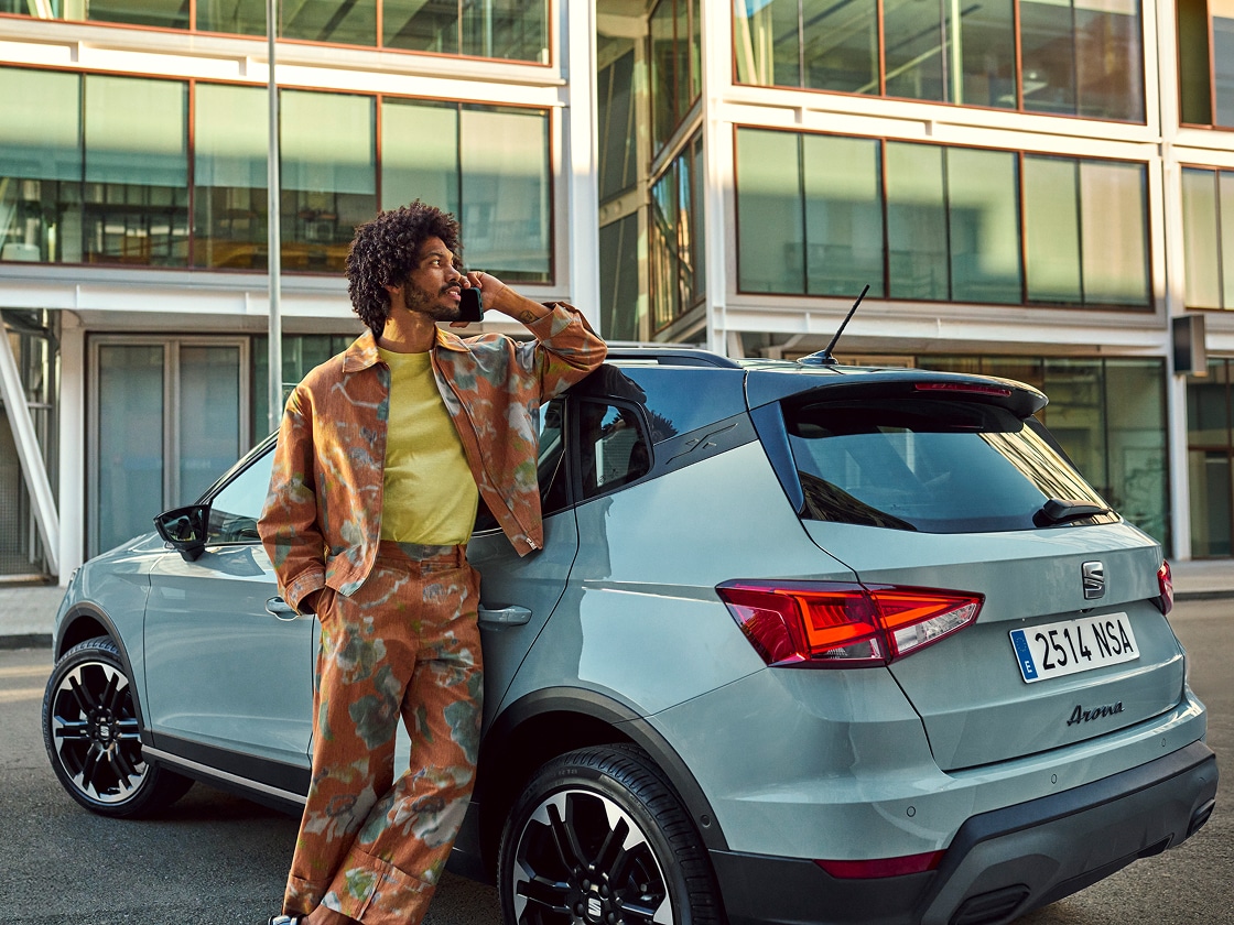 SEAT Arona parked in front of modern building with person calling for roadside assistance