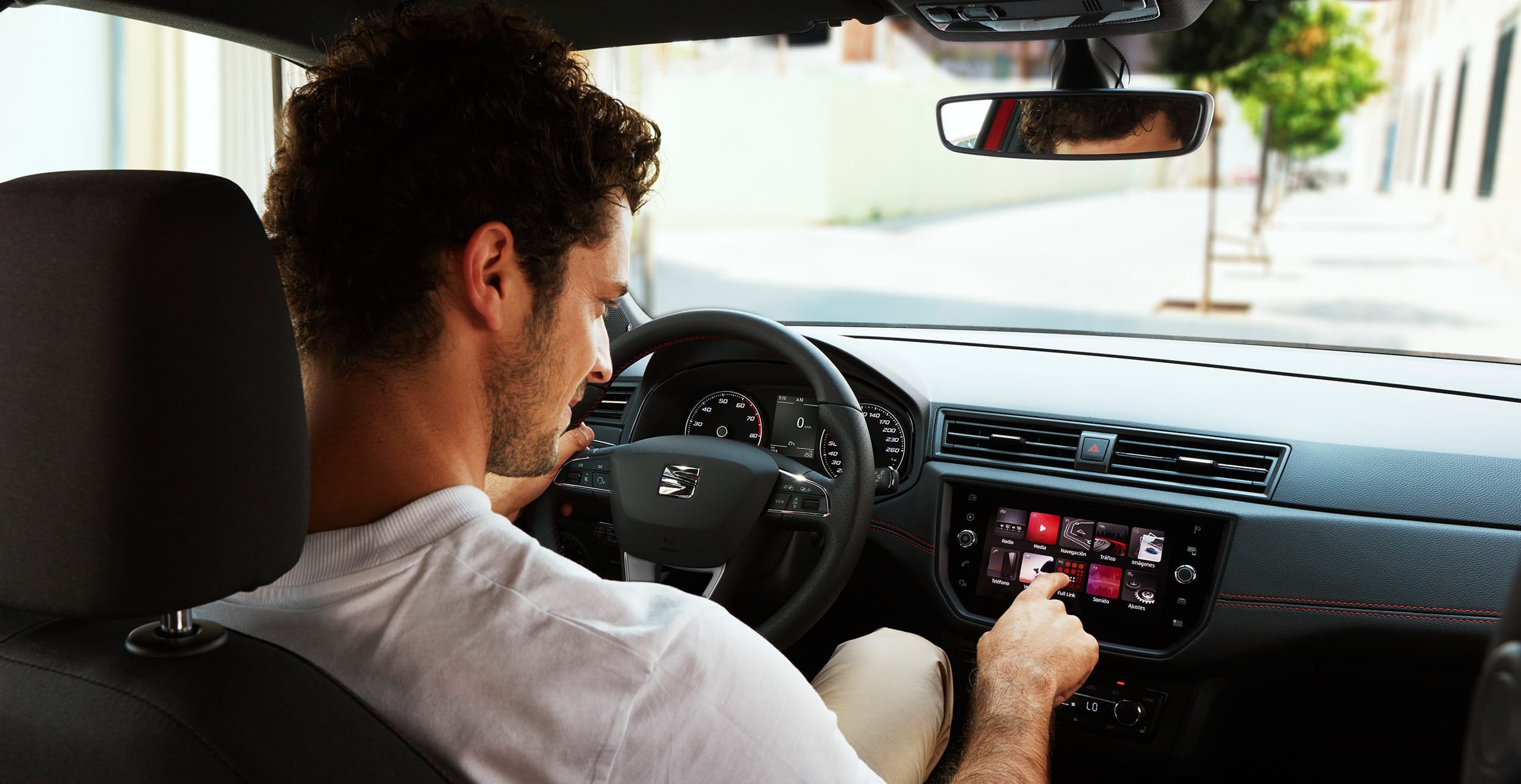 SEAT new car services and maintenance – interior rear view of a male driver pushing a button on the dashboard of a new SEAT car