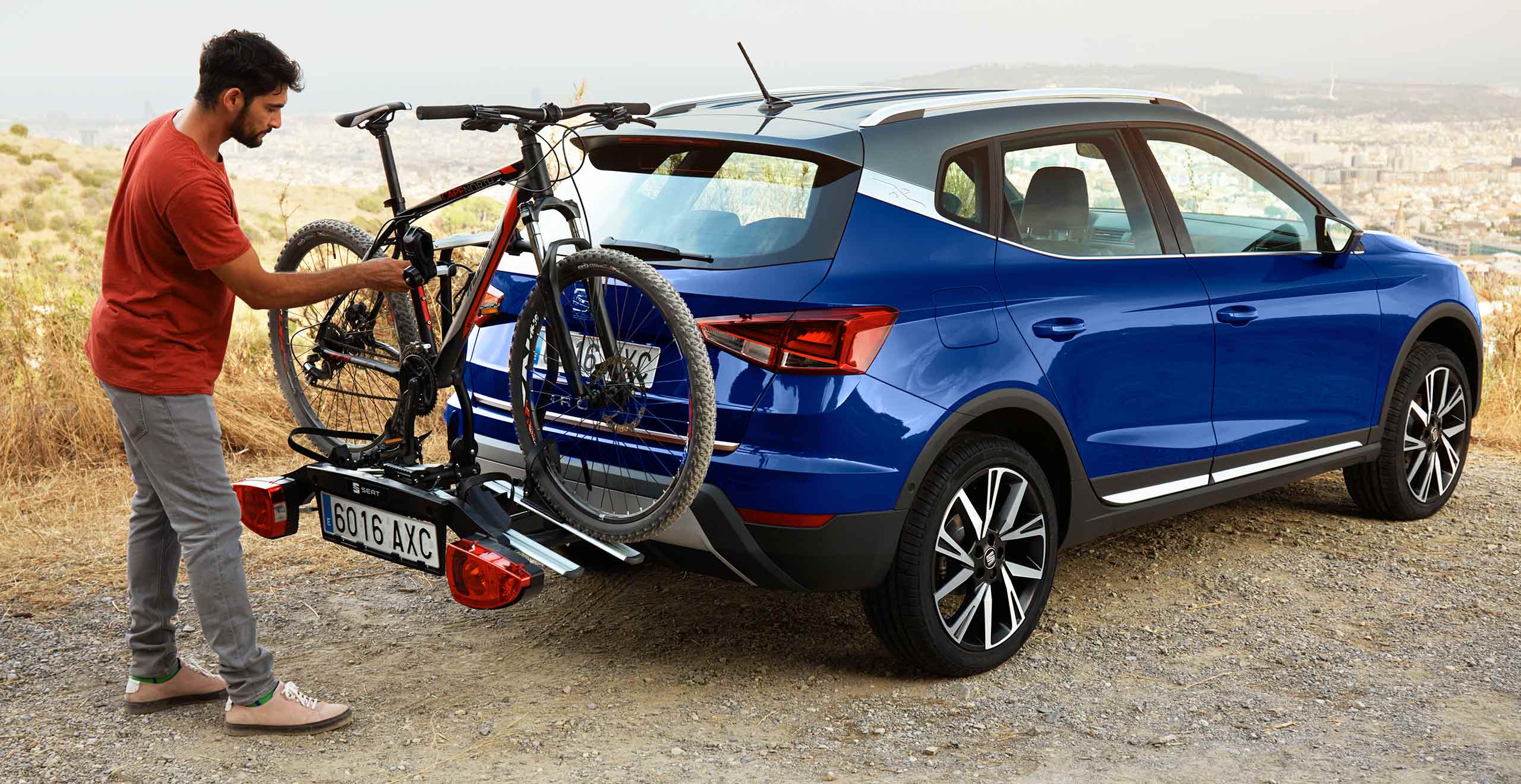 SEAT new car services and maintenance – man placing a bicycle on the bike rack at the back of a SEAT Arona crossover
