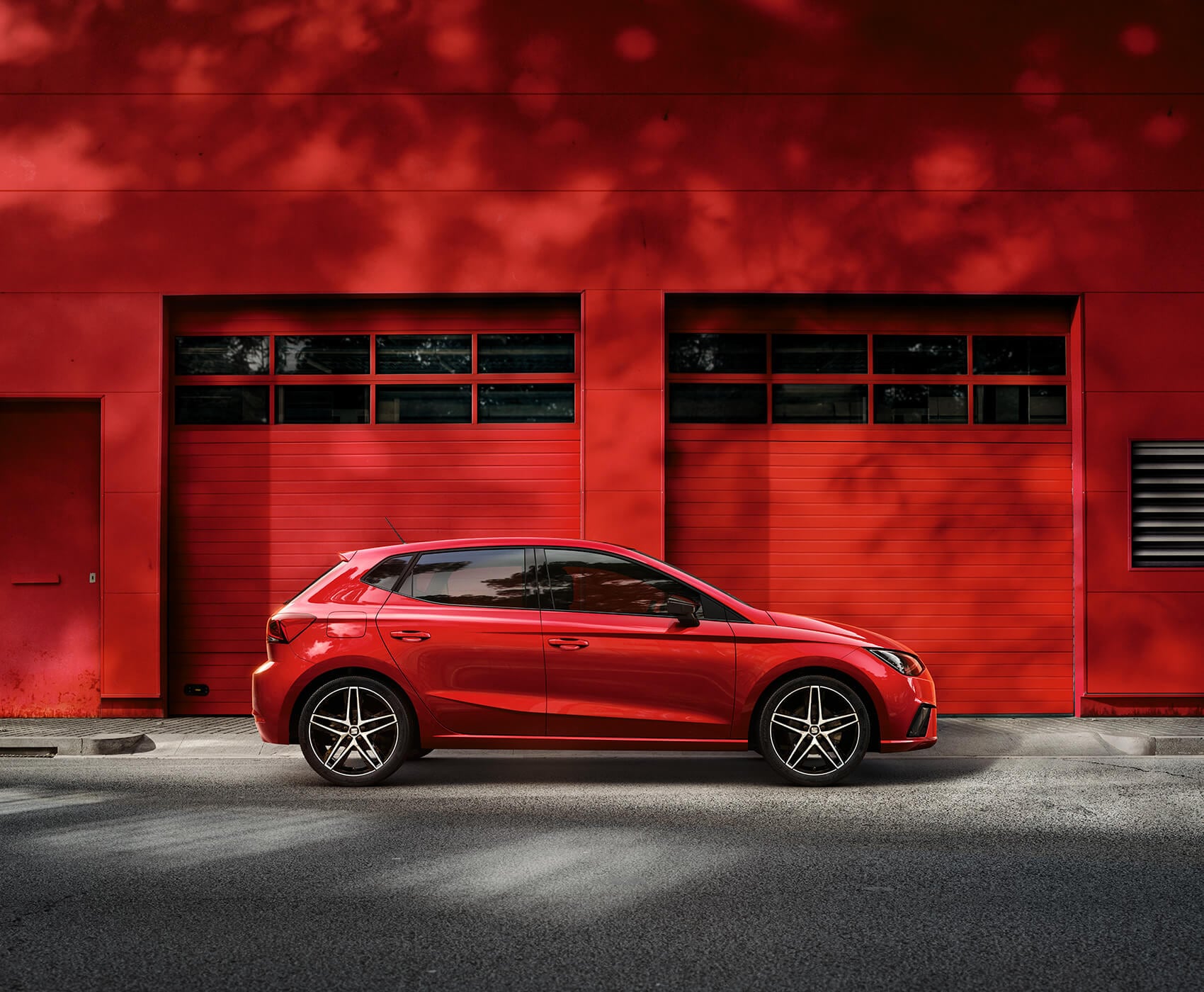 SEAT new car services maintenance independent garages – Red SEAT Ibiza city car hatchback parked in front of a red garage wall