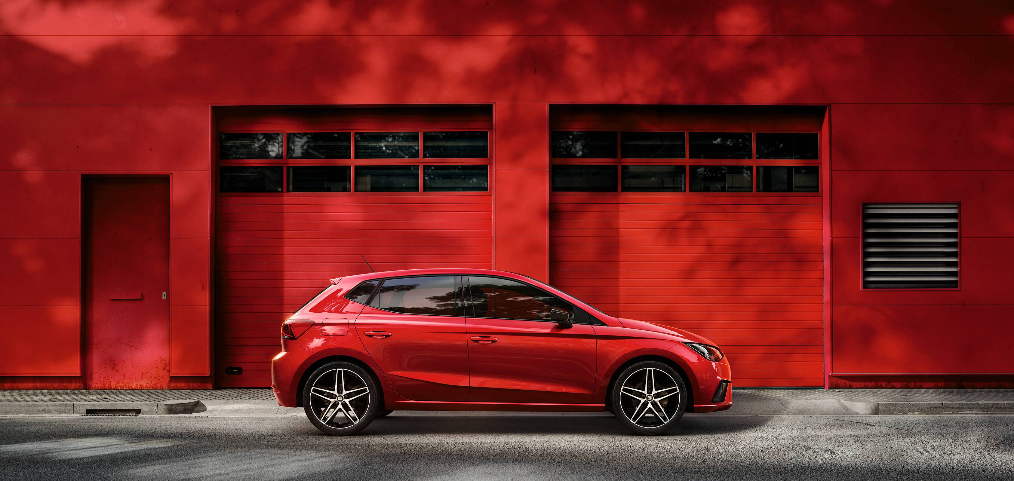 SEAT new car services maintenance independent garages – Red SEAT Ibiza city car hatchback parked in front of a red garage wall