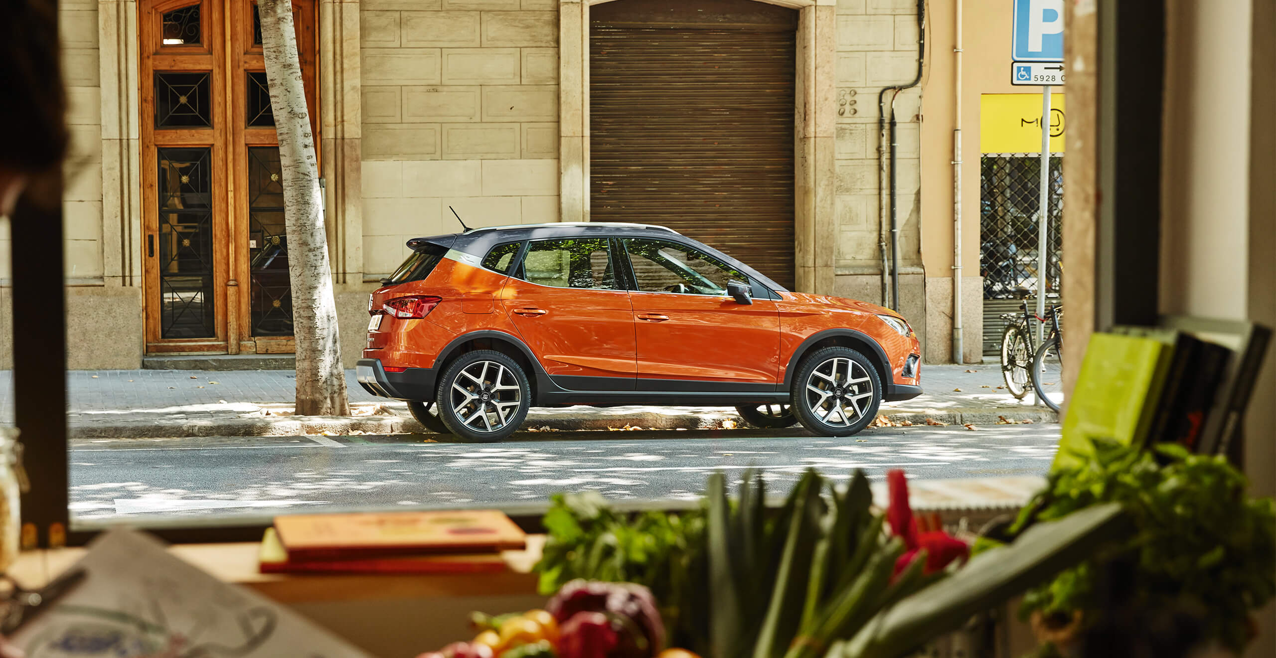 SEAT car pick up and delivery servicing and maintenance – View from inside a vegetable shop with a SEAT Arona crossover SUV seen outside through the window