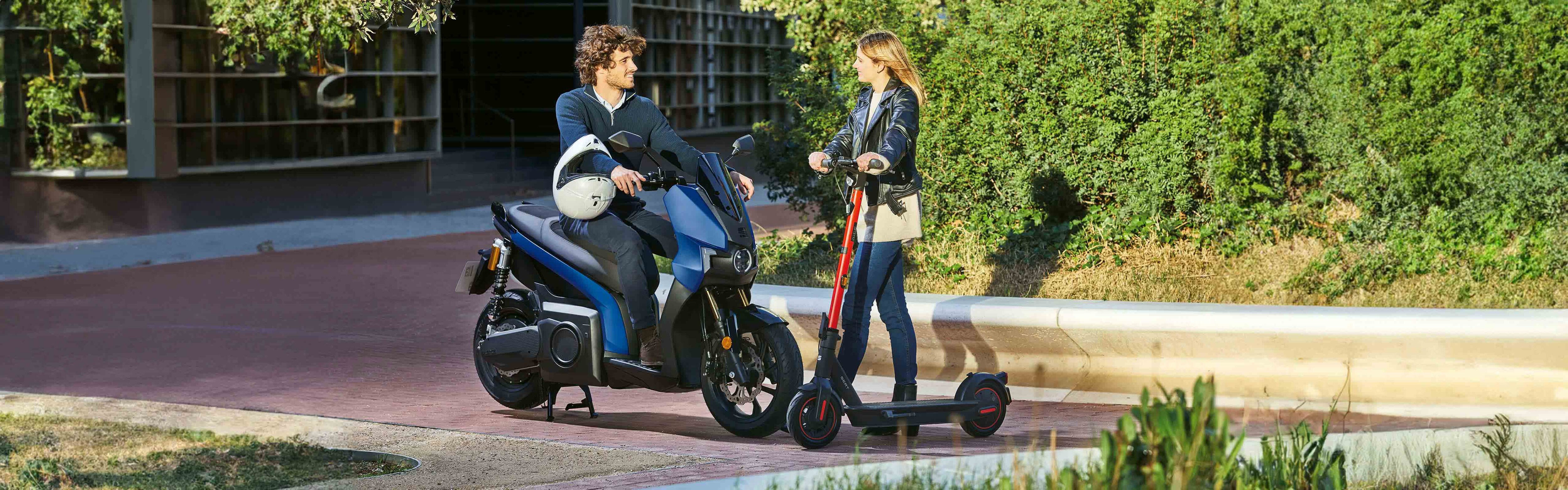 two friends talking in a SEAT MO 125 scooter and SEAT MO 65 kickscooter